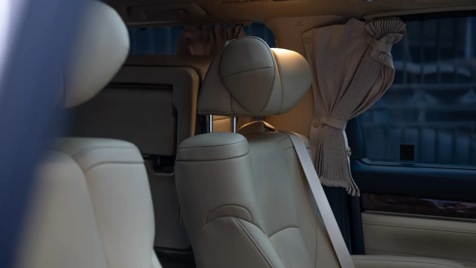 Cream leather captain seats and window curtains inside a Toyota Alphard private tour car