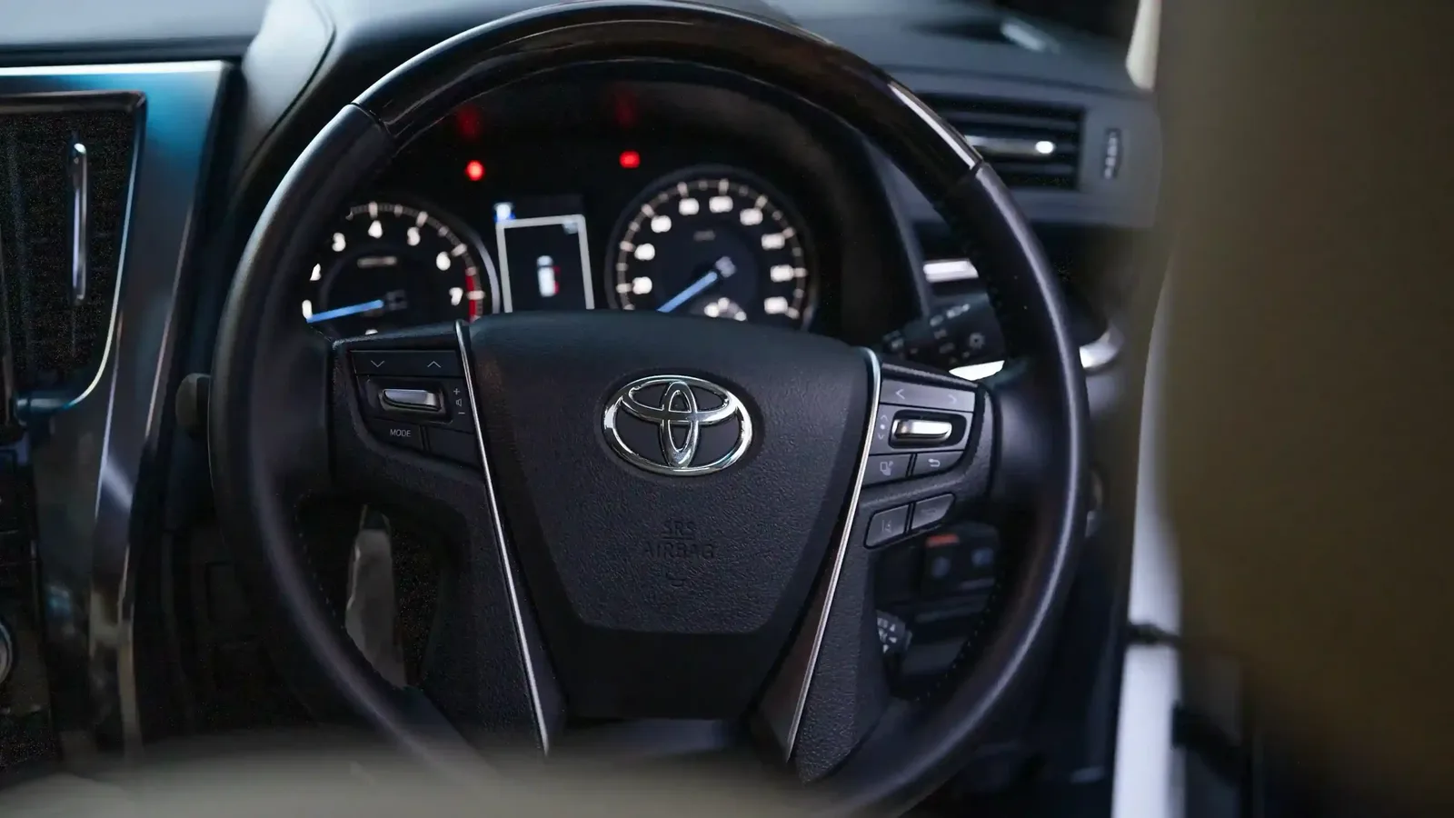 Driver's view of the Toyota steering wheel and instrument cluster in a Bali Alphard tour car